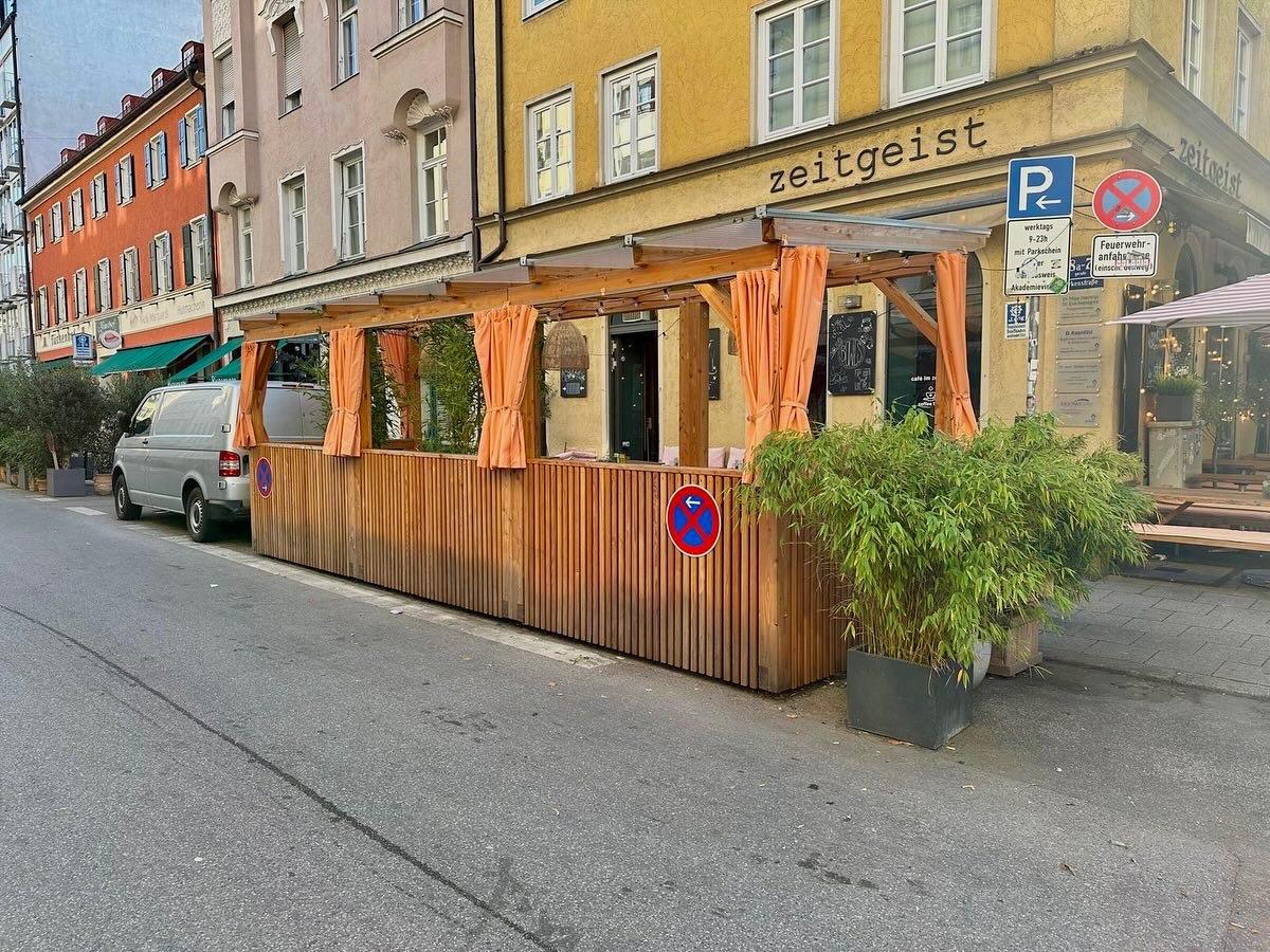 Naturholz-Terrasse der Bar zeitgeist in München mit Terrakotta-Vorhängen und Bambus